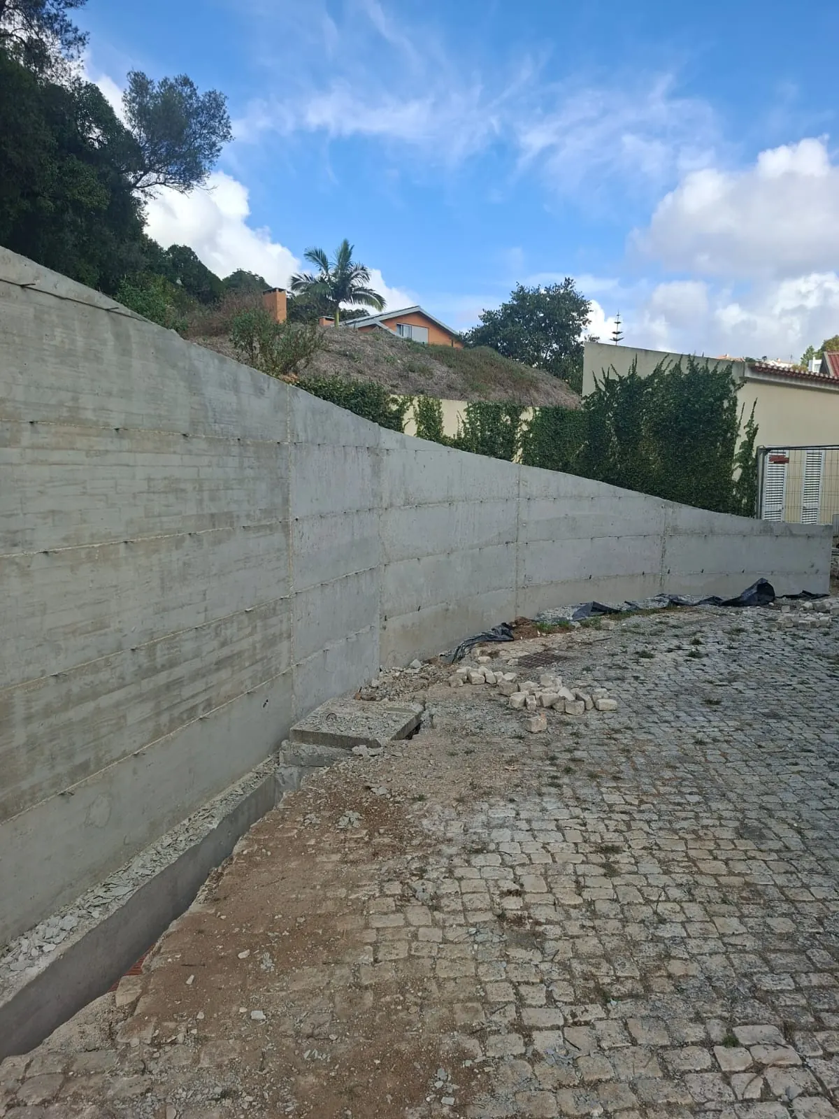 Muro de betão ao longo de uma faixa de terreno junto a vegetação.